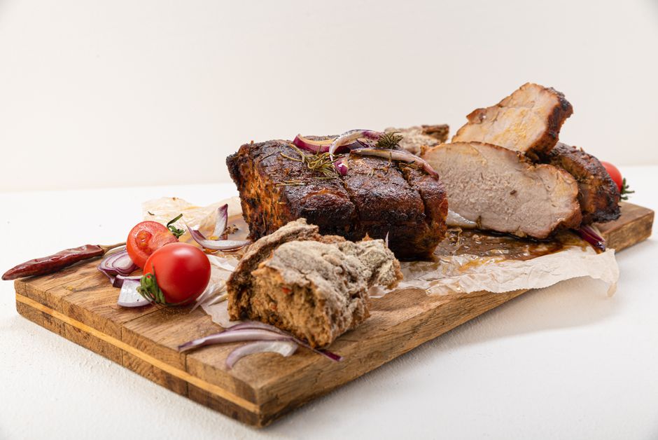 Tantalizing roast pork with veggies on a rustic wooden board. Perfect for dinner ideas.